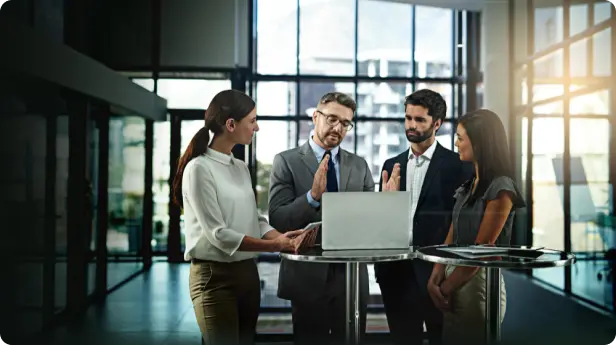 Corporate training discussion around a shared workstation.